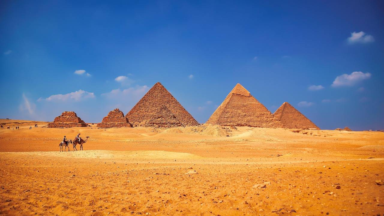 Pyramidy v Gíze a karavana velbloudů v poušti